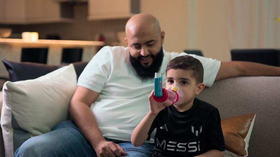 Jassem sits next to his dad Abdulrahman Alameeri with his inhaler