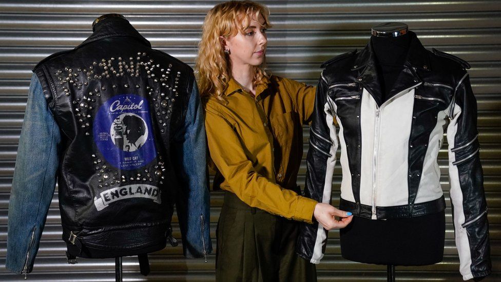 A Propstore employee adjusts Michael Jackson's custom-made leather jacket from a 1984 Pepsi New Generation commercial, which is next to George Michael's screen matched La Rocka Jacket from the music video for 'I Knew You Were Waiting (For Me)' during a preview for the Entertainment Memorabilia Auction, at the Propstore in Rickmansworth, Hertfordshire.