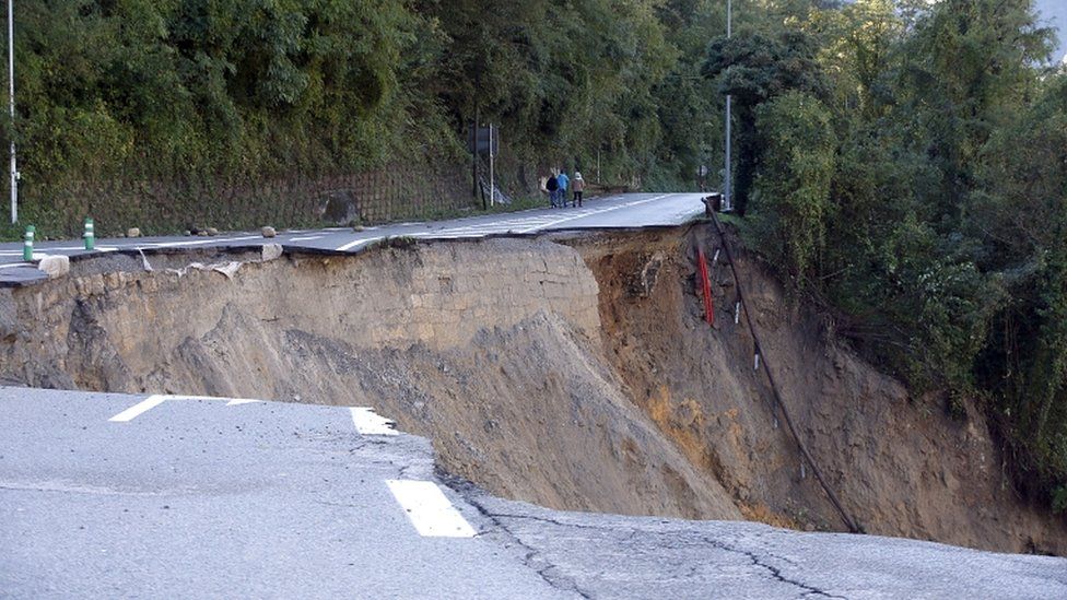 People walk on a collapsed road along the Vésubie river that was partially washed away because of heavy rains brought by Storm Alex in Roquebillière, France, on 3 October 2020