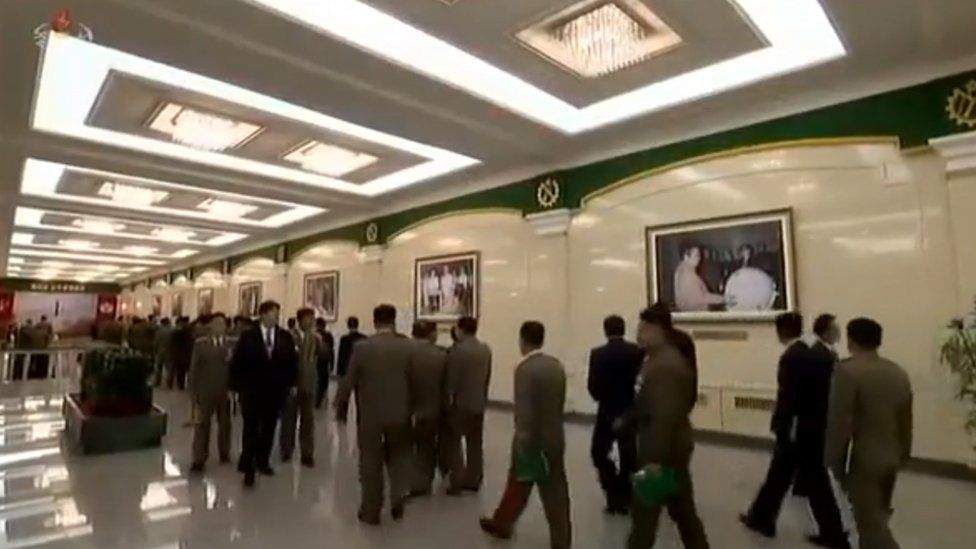 Delegates walk in front of a picture of Kim Il-sung at a munitions industry conference in Pyongyang