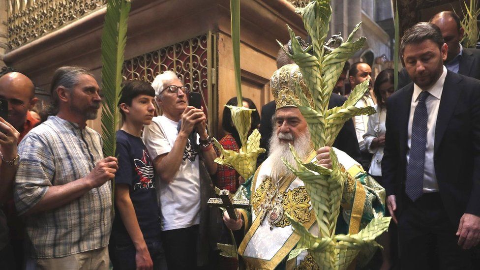 Greek Orthodox Patriarch of Jerusalem Theophilos III (C) holds palm branches as he takes part in an Orthodox Palm Sunday procession in the Church of the Holy Sepulchre in Jerusalem on 9 April 2023