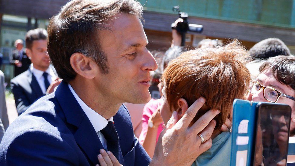 Президент Франции Эммануэль Макрон целует ребенка во время первого тура парламентских выборов во Франции на избирательном участке в Ле-Туке, Франция, 12 июня 2022 года.