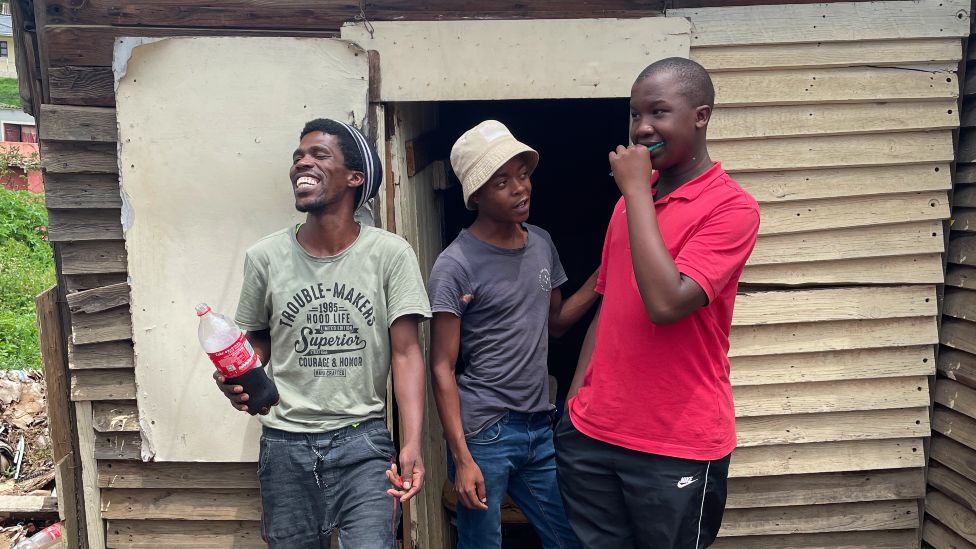Трое мужчин, один смеющийся, в районе Умлази к югу от Дурбана, Южная Африка - декабрь 2021 г.
