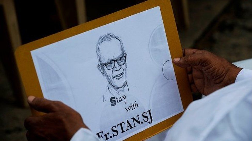 A Catholic priest holds a placard with the image of Jesuit priest Father Stan Swamy during a protest against his arrest in the eastern Indian state of Jharkhand .