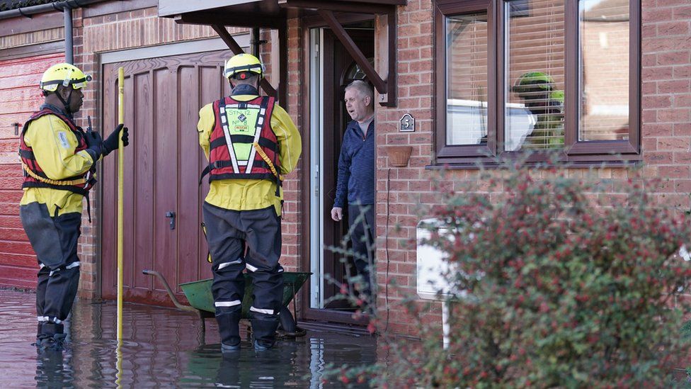 Rescue workers talk to a man on his doorstep amid flooding in Retford in Nottinghamshire, after Storm Babet battered the UK.