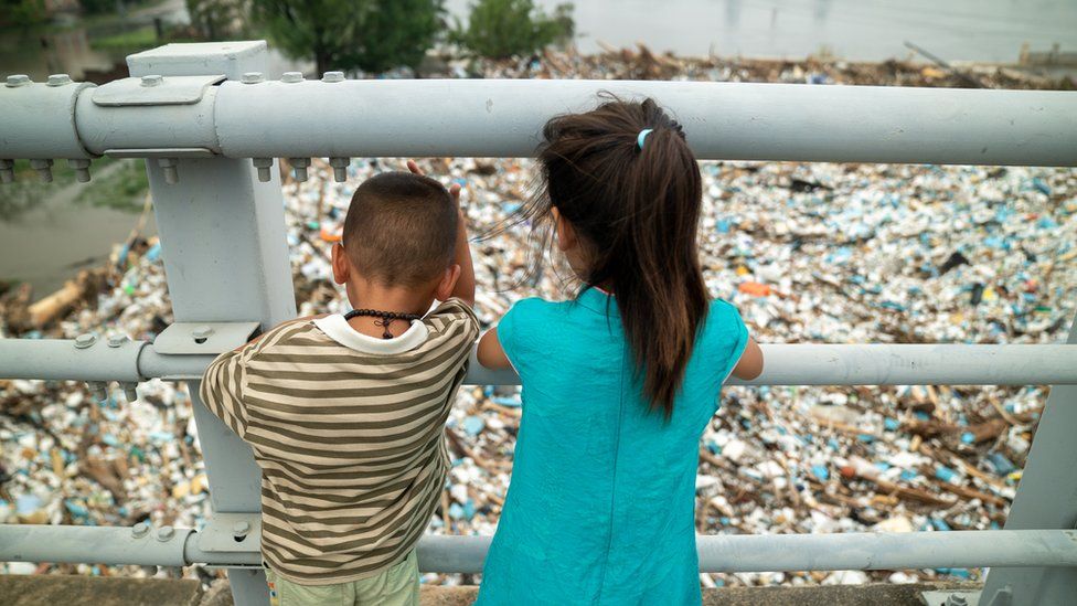 Children look at an island of rubbish