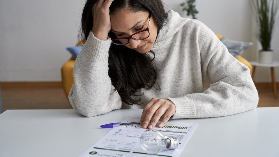 A woman looking worries as she looks at her bill