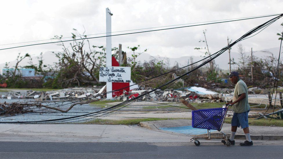 A man pushes a shopping basket past downed powerlines