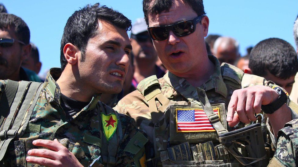 File photo from 25 April 2017 showing US military officer speaking to Syrian Kurdish People's Protection Units (YPG) fighter near Derik, Syria