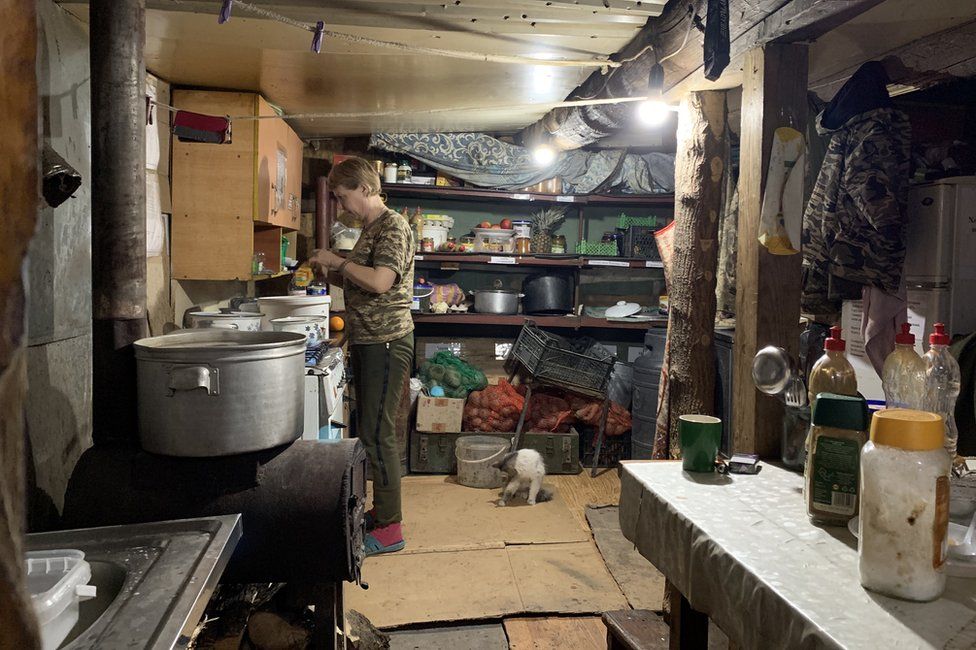 A Ukrainian soldier prepares food in a makeshift kitchen near the front lines