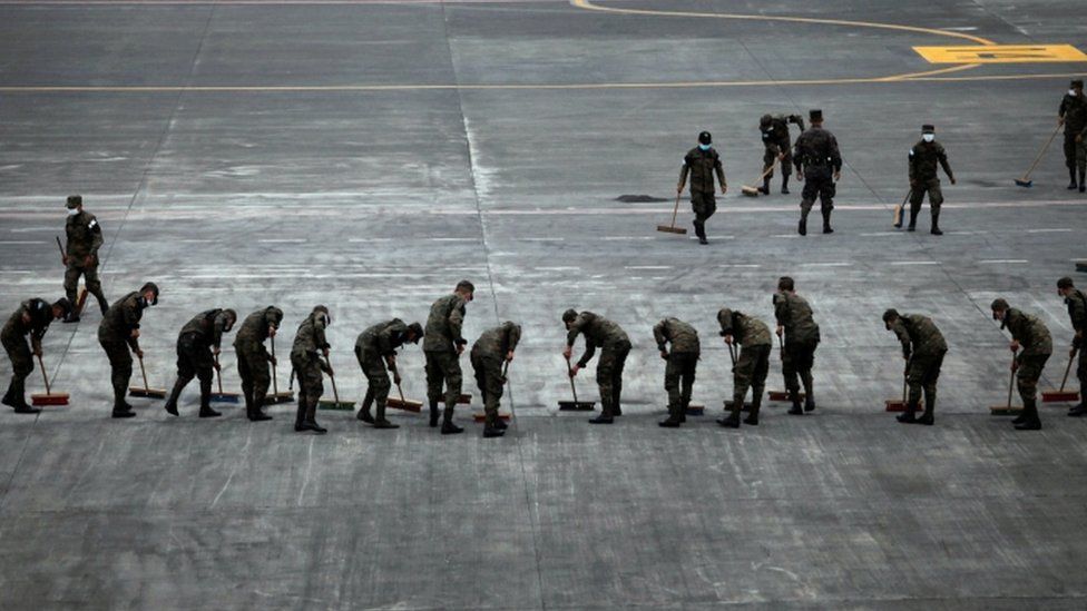 Soldiers sweep the ash covered tarmac at La Aurora International Airport