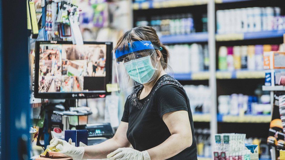 A woman wearing protective gear working in a supermarket in Asia