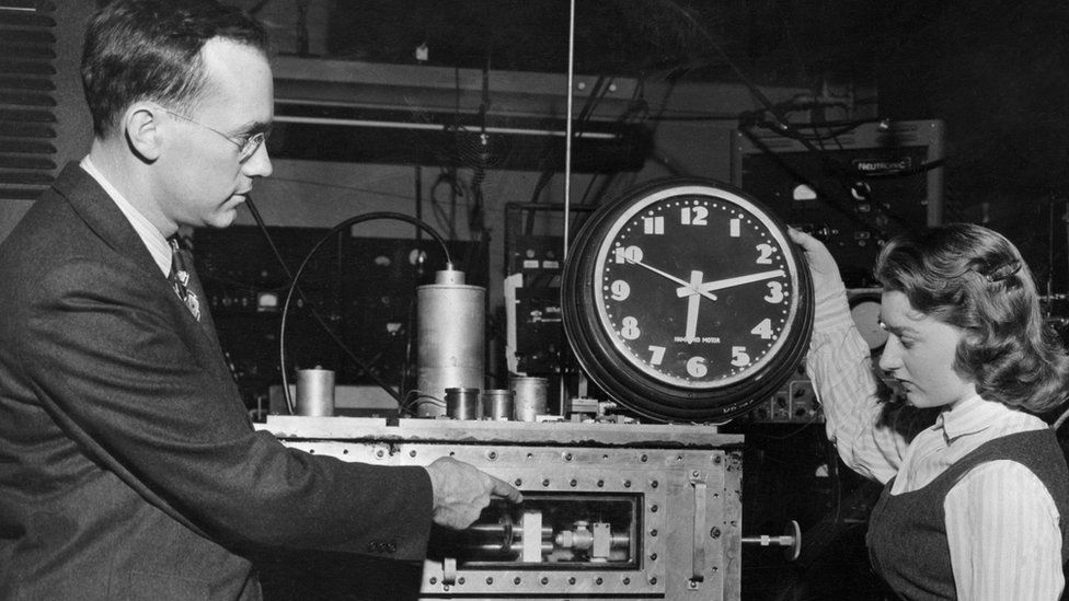 Charles H. Townes, Columbia University professor who invented the "Maser," shows Marianne MacDonald how the atomic clock differs from common electric clock. The "Maser" can divide a second accurately into 24 billion parts.