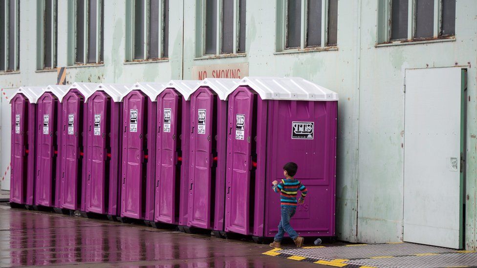 A small boy heads to a portable toilet in front of a hangar at the former Tempelhof Airport in Berlin, Germany (9 December 2015)