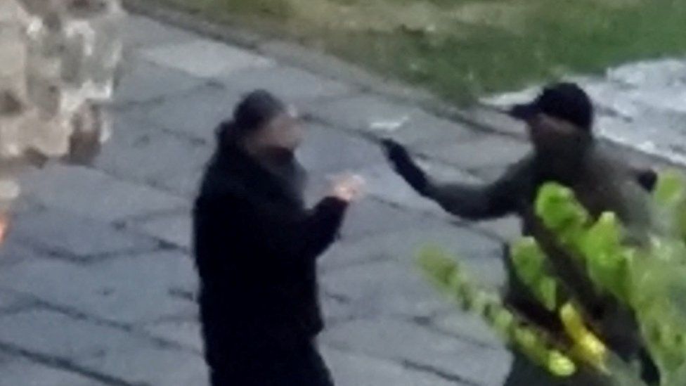 An armed man talks with a priest inside a monastery at a place given as Banjska, Kosovo