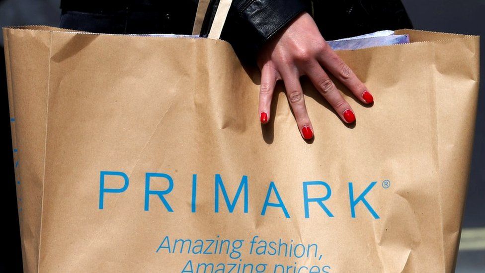Shopper walking past a branch of clothing retailer Primark