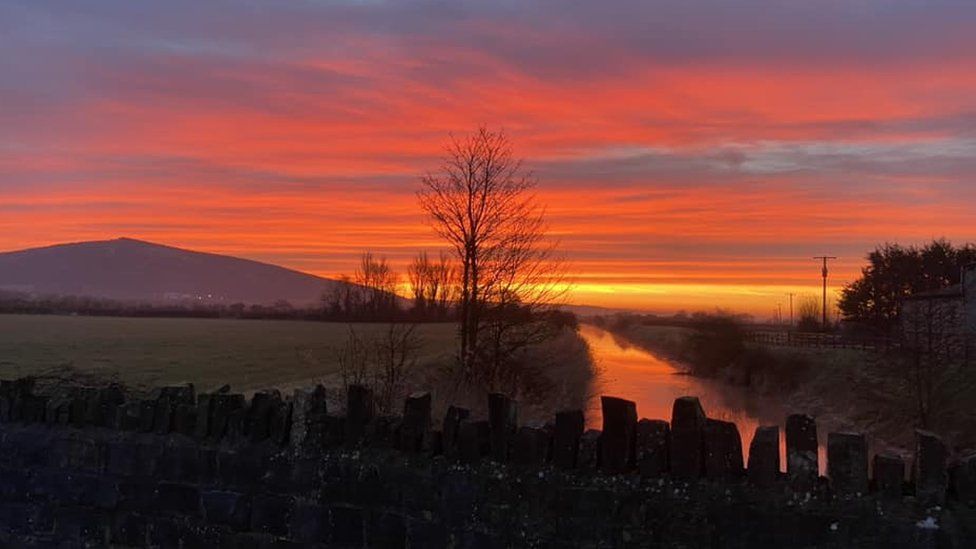 A sunrise above a river with a hill in the background in Loxton