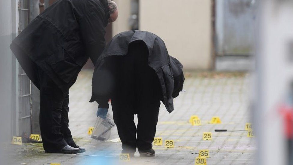 Investigators bend over markers on the ground during investigations at the crime scene in Berlin, Germany, 26 December 2020.
