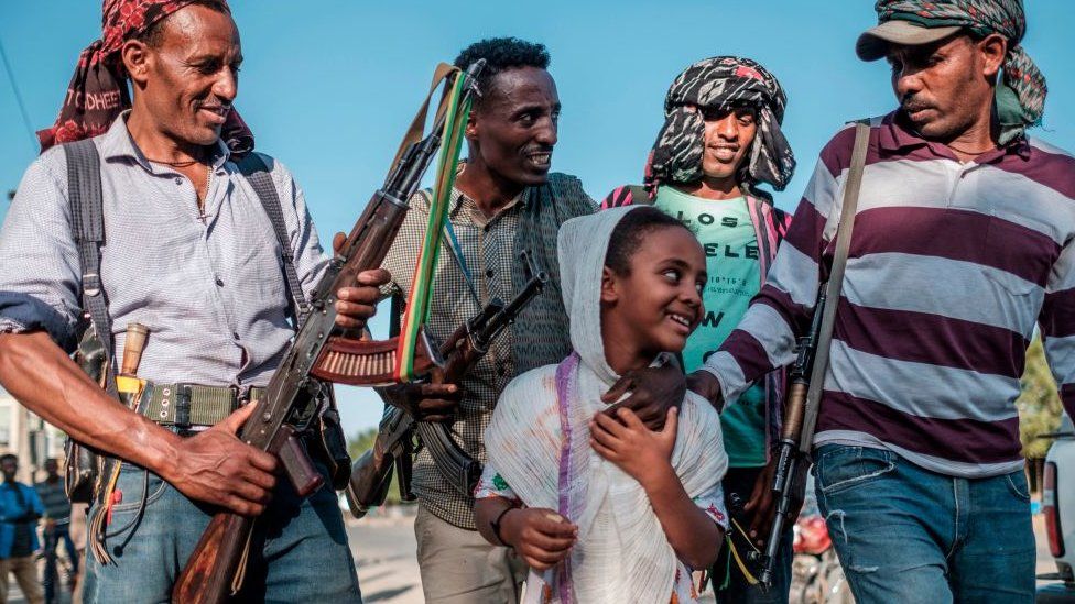 Ethiopian Amhara fighters in Mai Kadra, Tigray region, posing for a photo with a young girl - 21 November 2020