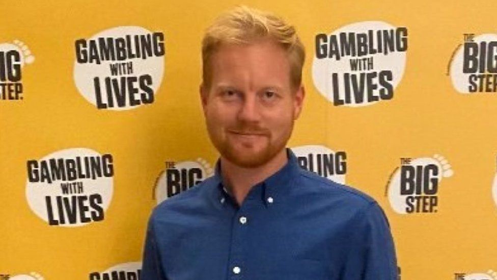 James Grimes standing in front of a Gambling with Lives banner