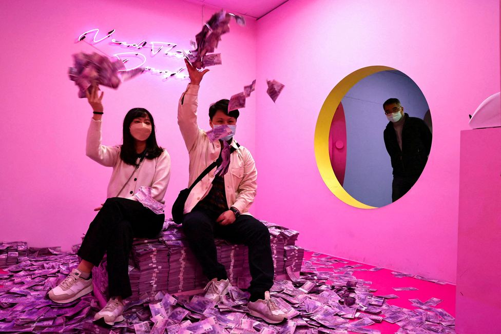 People throw printed money in the air at a pop-up museum in Taipei