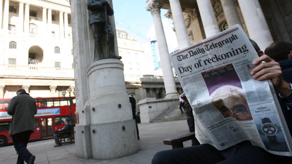Man reads newspaper outside the Bank of England