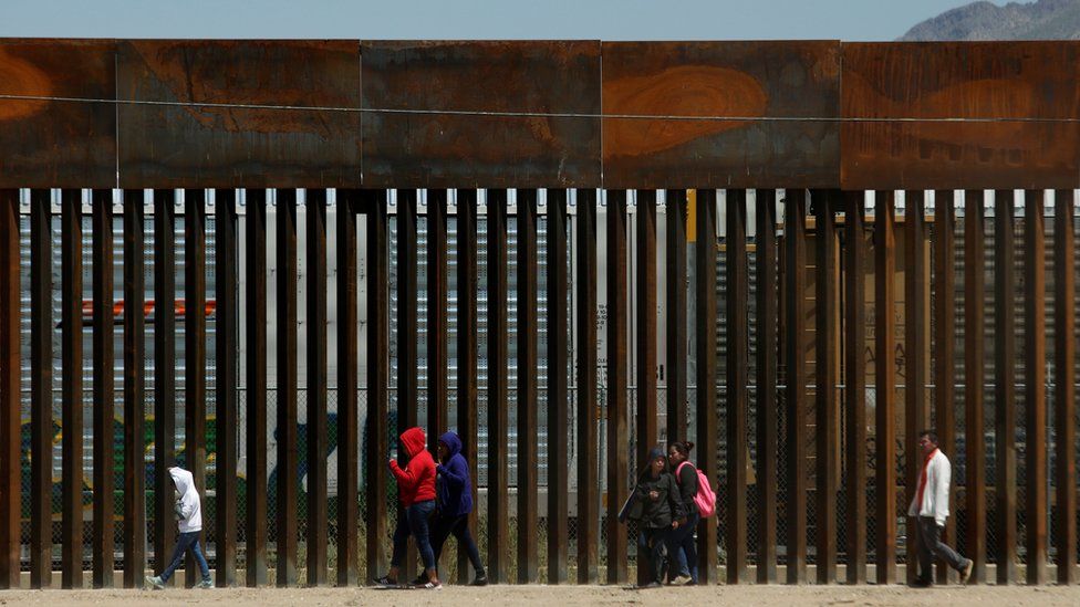 Migrants walk along the border fence after crossing illegally into El Paso, Texas