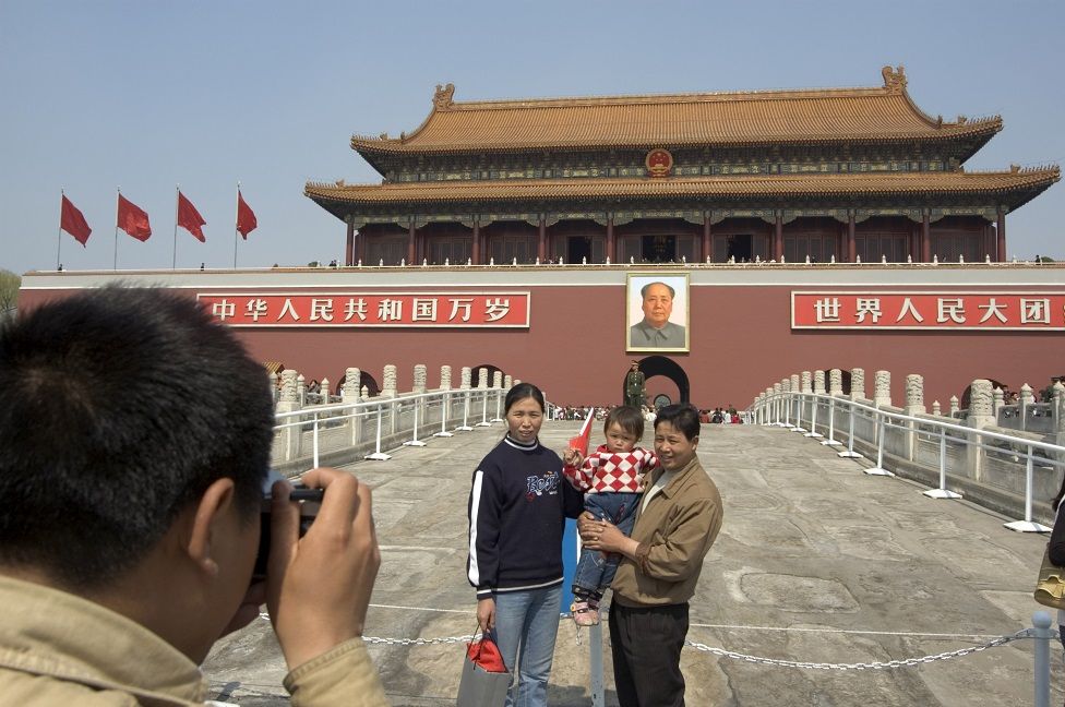 Chinese tourists pose for pictures in front of Mao's portrait at Gate of Heavenly Peace in Tianenman Square