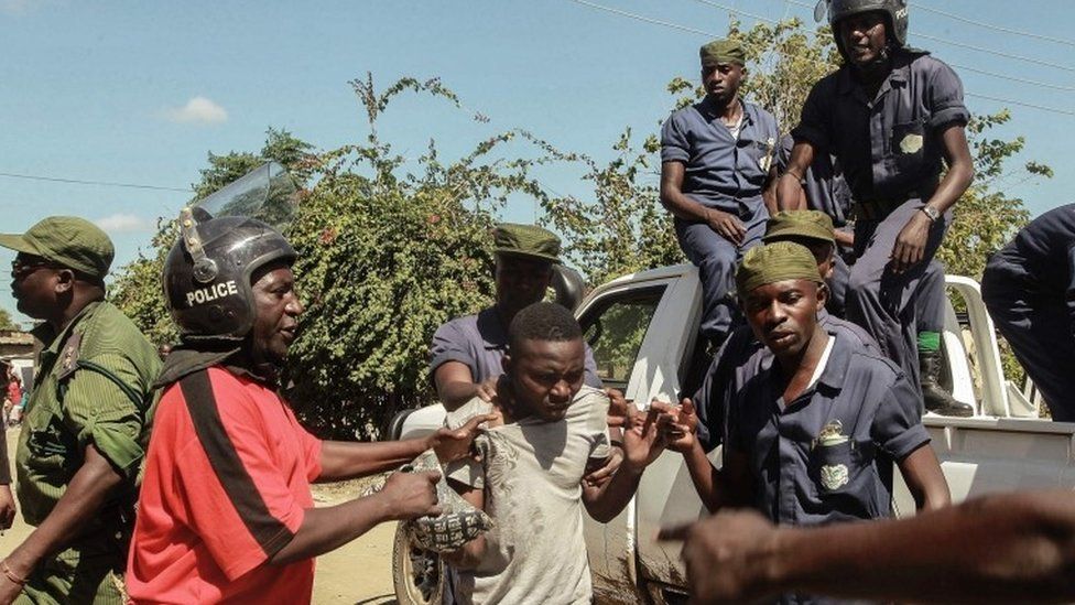 Zambian Police apprehend an alleged looter in the Zingalume Compound where residents have attacked broken and looted foreign-run shops in Lusaka on April 19, 2016