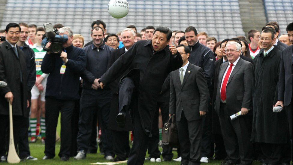 Xi Jinping kicking a football in front of a crowd