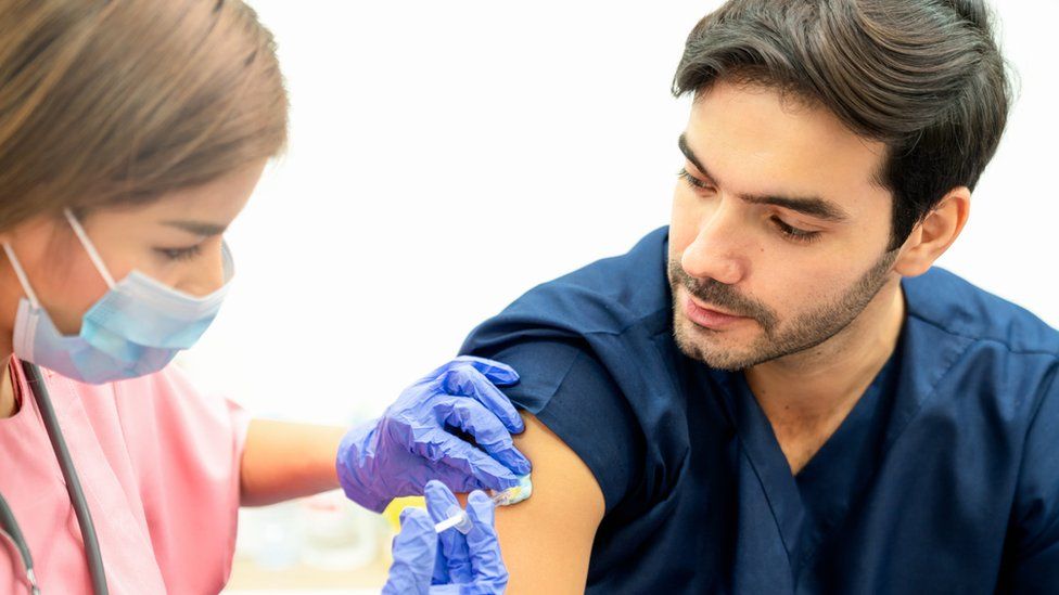 A caregiver  administers a vaccine to a male