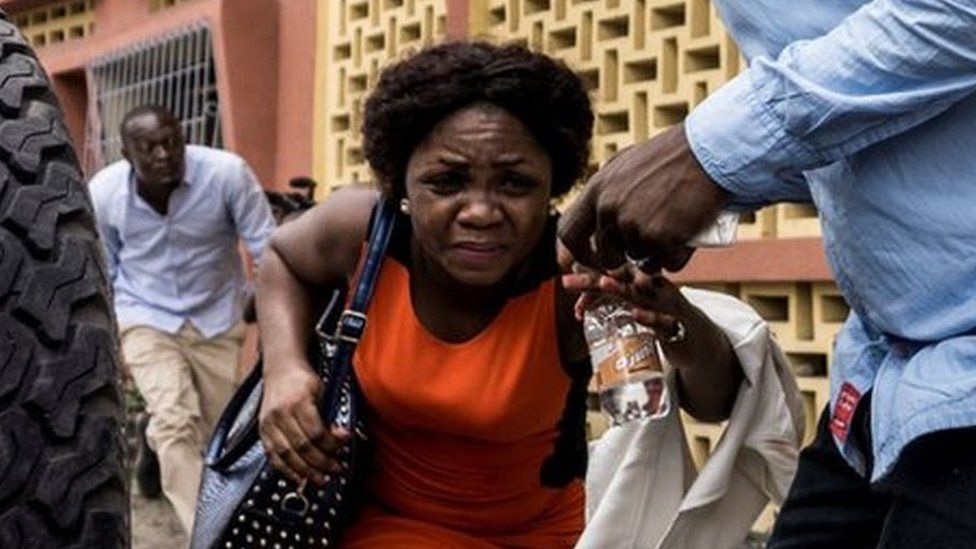A woman runs for cover in Kinshasa