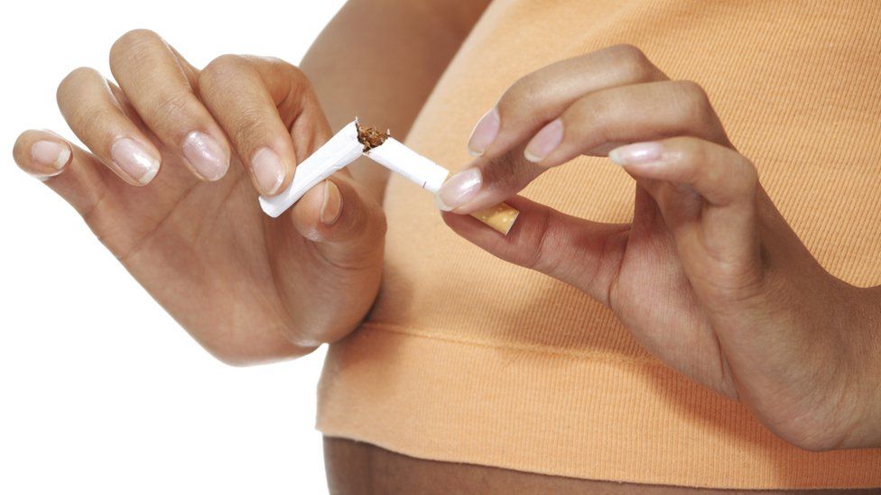 pregnant women breaking a cigarette