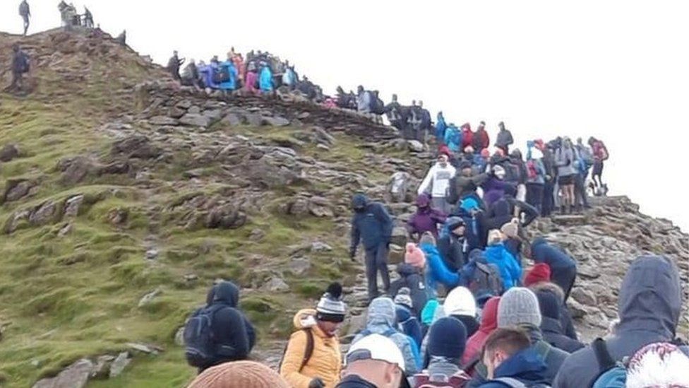 Crowds of people gathering and queuing to get to the top of Snowdon