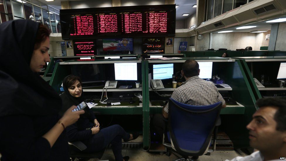 Iranian dealers chat next to an activity board at the stock exchange in the capital Tehran
