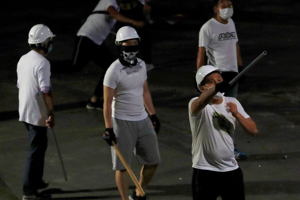 Men in white T-shirts with poles are seen in Yuen Long after attacked anti-extradition bill demonstrators at a train station, in Hong Kong, China July 22, 2019.