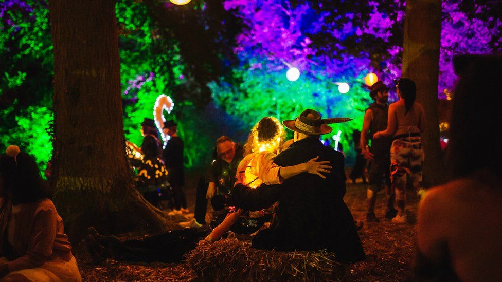 A couple sitting on a haystack at Shambala Festival at night