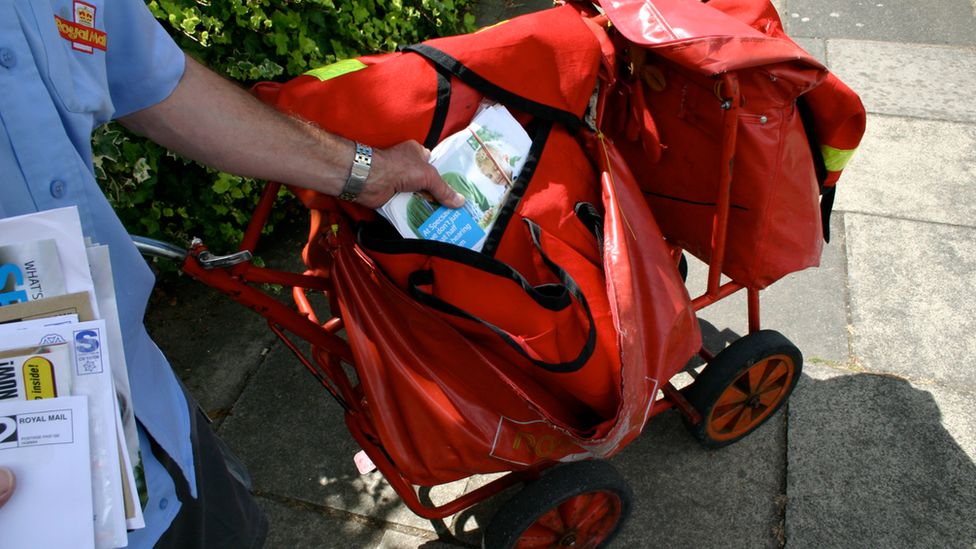 Postman reaching into trolley for letters