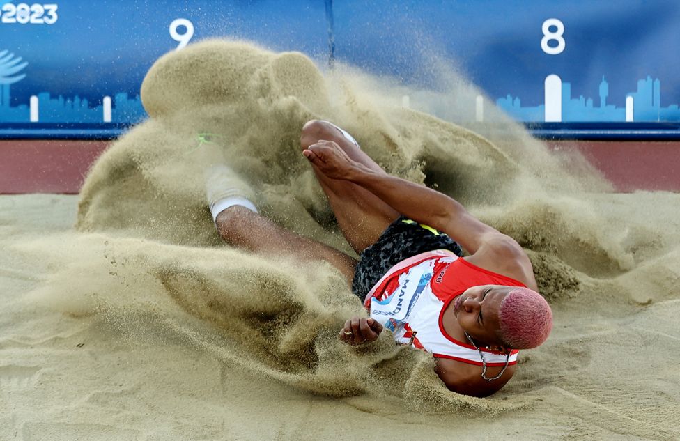 Jose Luis Mandros is covered in sand as he participates in the long Jump during the Pan-Am Games in Santiago