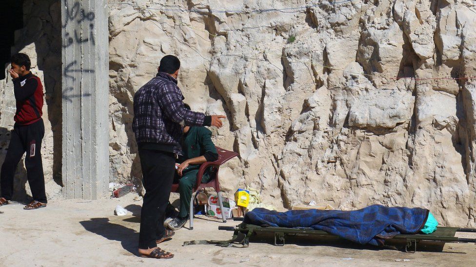 A man stands near a dead body on a stretcher after a suspected chemical attack in Khan Sheikhoun, Idlib province, Syria (4 April 2017)
