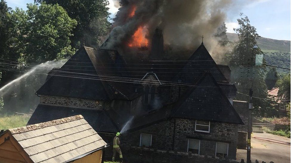 A firefighter battles the fire as flames tear through Dolgerddon Hall