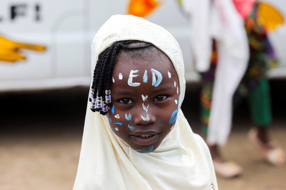 A girl has the word 'Eid' daubed on her forehead with face paint.