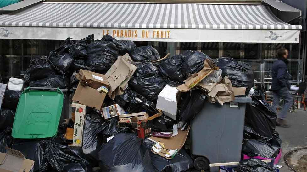 Overflowing garbage bins crowd sidewalks in Paris