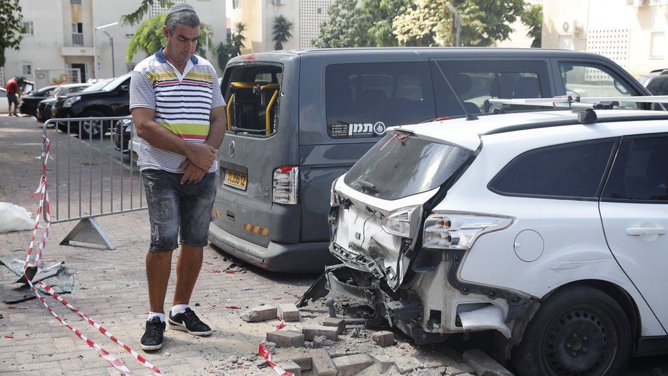 An Israeli man inspects damage to a car caused by a rocket fired from Gaza (9 August 2018)