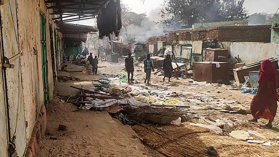 People walk among scattered objects in the market of El Geneina, the capital of West Darfur, as fighting continues in Sudan between the forces of two rival generals, on April 29, 2023.