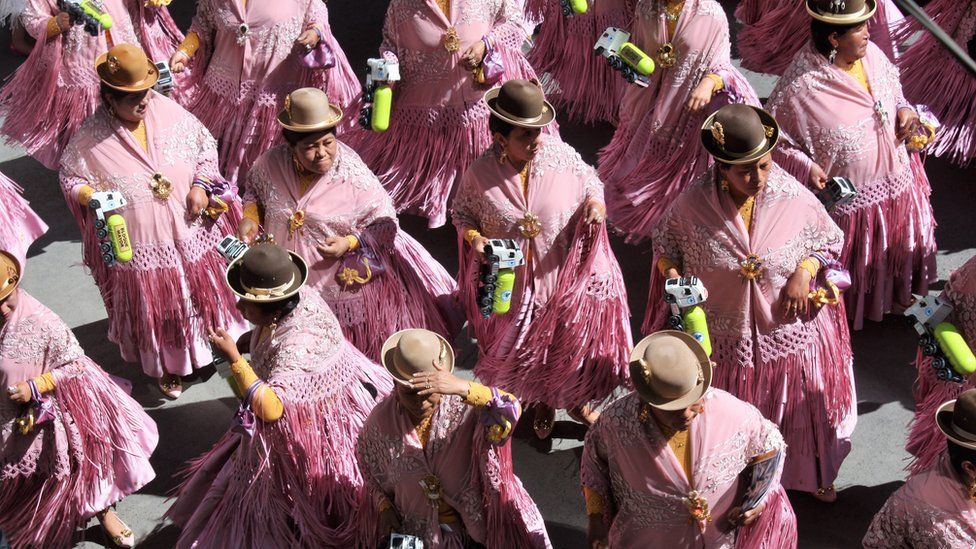 Dancers in pink shawls and bowler hats perform