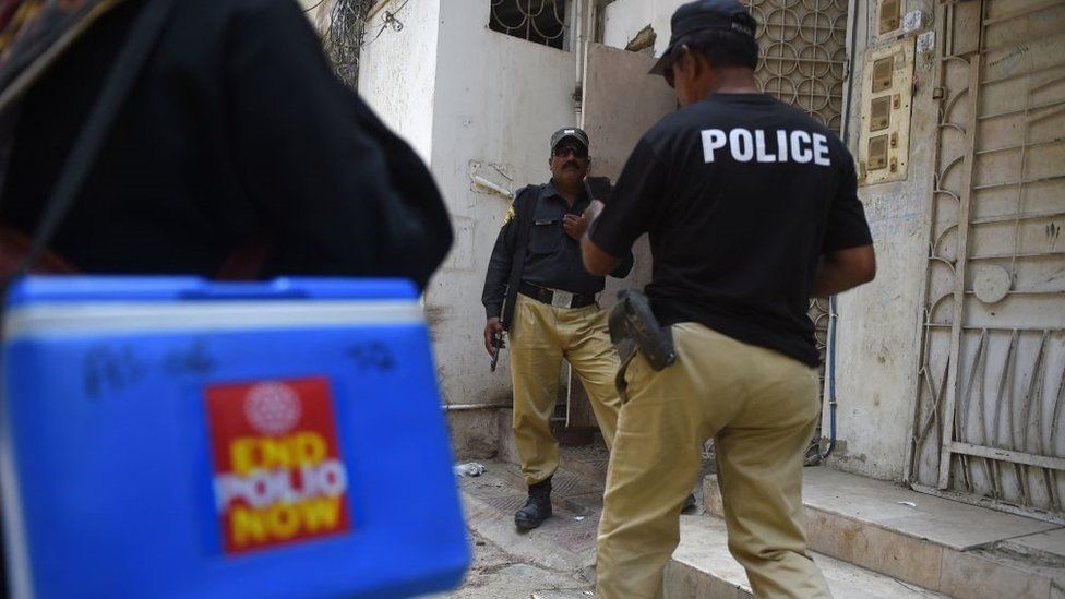 Two policemen and a polio vaccinator