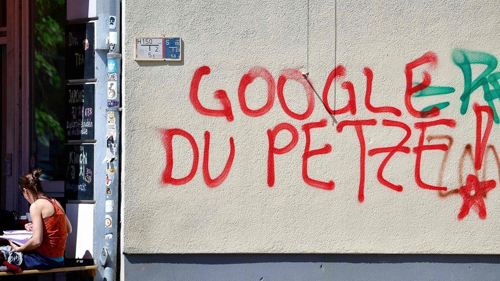 A woman sits next to anti-Google graffiti in Kreuzberg