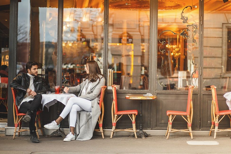 A couple sit outside a cafe in Paris