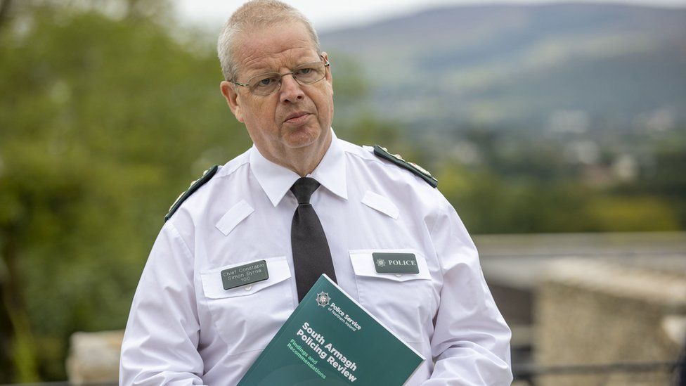 Simon Byrne holding a copy of the south Armagh policing review